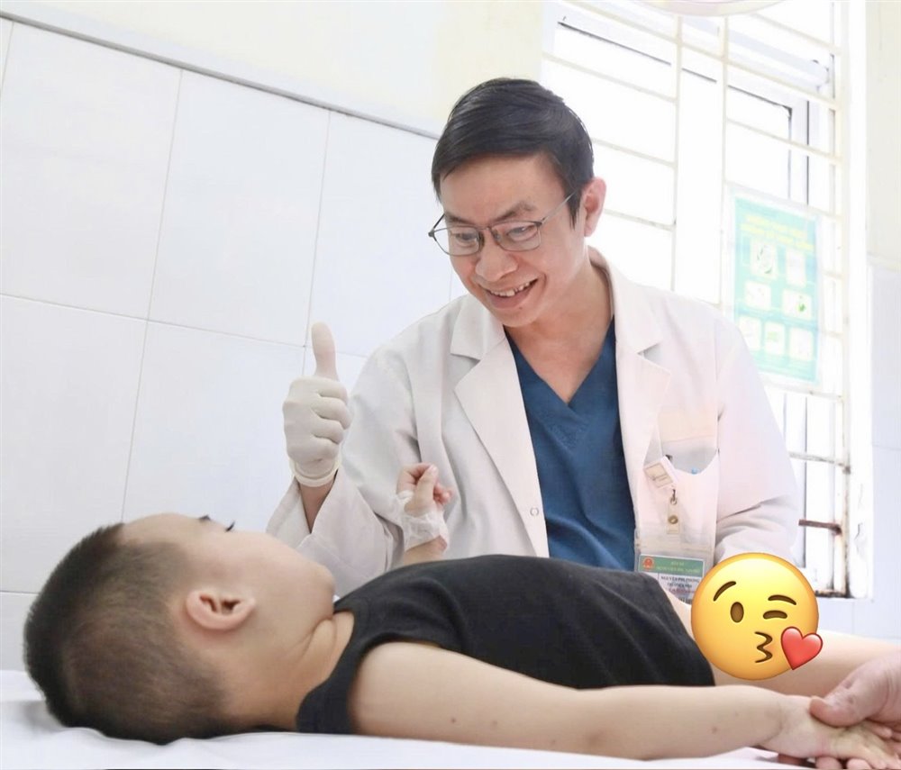 BS Nguyễn Phi Phong động viên một bệnh nhi sau khi khám